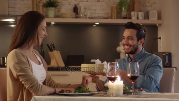 Pareja teniendo una cena romántica. Hombre guapo le da a su novia una caja de regalo. Ella Bemusedly acepta . — Vídeos de Stock