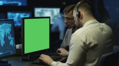 Konsantre programcılar bir sistem kontrol odasında bulunan kişisel bilgisayarlarda çalışır. Bilgisayar yeşil ekrana sahip.