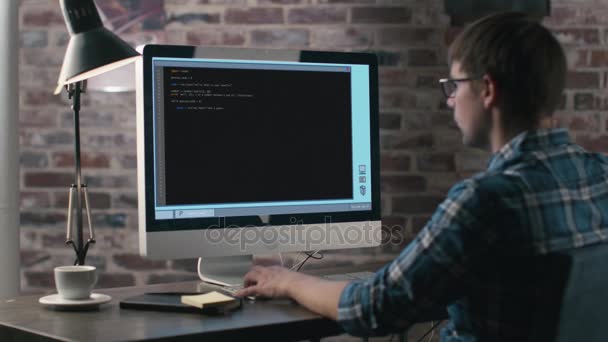 Молодой кавказский программист, работающий за компьютером в своем офисе . — стоковое видео