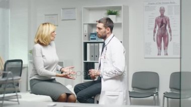 Genç erkek doktor onun orta yetişkin Bayan hasta danışır. Onlar kontrol Her ellerin.