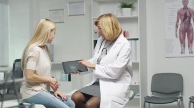 Yetişkin kadın doktor ultrason görüntüsü ile onun Tablet bilgisayara göstererek genç erkek danışır.