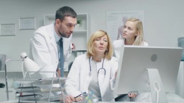 Üç doktorlar tartışmak tıbbi sorunları kişisel bilgisayar önce dururken