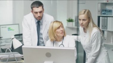 Tıbbi personel tartışmak iş ilgili sorunları kişisel bilgisayar kullanarak tamamlayın. Erkek doktor Puan ekranında. 