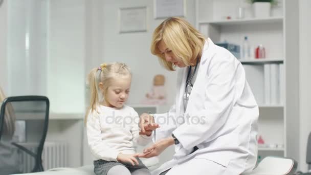 Γιατρός θηλυκό κάνει εξέταση των χεριών ενός μικρού κοριτσιού. Νοσοκόμα λειτουργεί στο παρασκήνιο. — Αρχείο Βίντεο