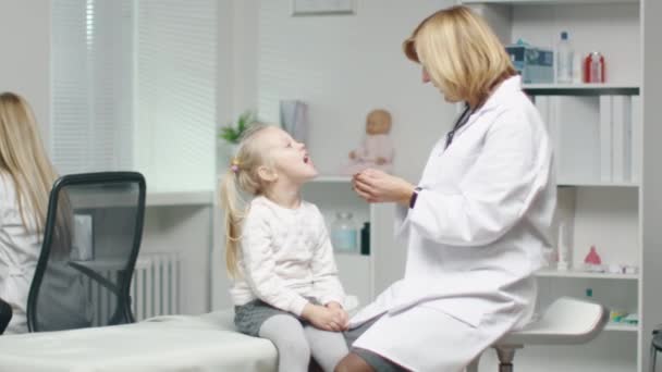 La doctora hace el examen de garganta de una niña. Después del examen hacen Choca esos cinco . — Vídeo de stock