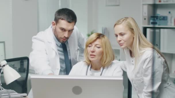 Медичний персонал обговорює проблеми, пов'язані з роботою, використовуючи персональний комп'ютер. Вони вказують на екран і розмовляють . — стокове відео