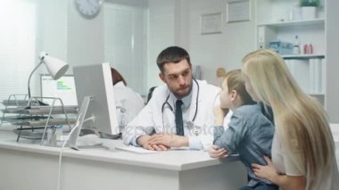 Genç anne ve küçük oğlu, doktor. Yakışıklı erkek doktor inceler ve erkek çocuk için görüşmeler.