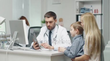 Erkek doktor genç çocuk ve annesi bir Tablet yardımıyla danışır.
