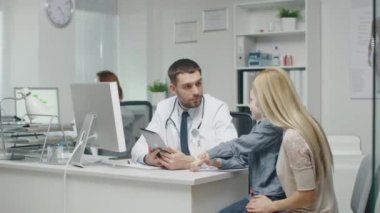 Hastanede. Yakışıklı doktor bir şey gülümseyen küçük bir çocuk ve annesi için bir Tablet bilgisayarda gösterir.