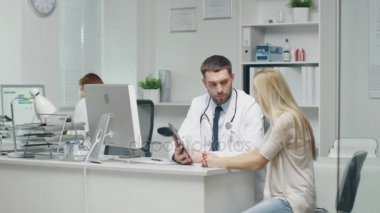 Doktor ofisinde genç hasta gülümsüyor ve Tablet tutar doktor danışır..