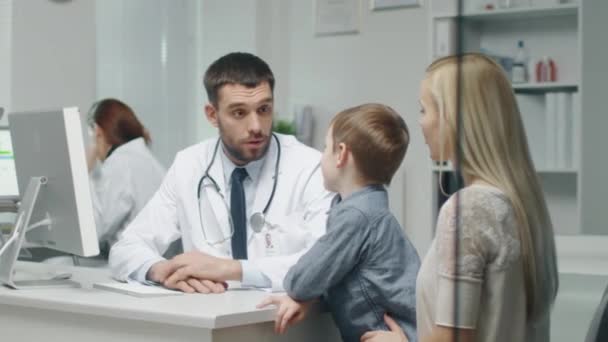 At Doctor's Office. Well Natured Male Doctor Talks and Jokes with Little Boy and His Mother. In Slow Motion. — Stock Video