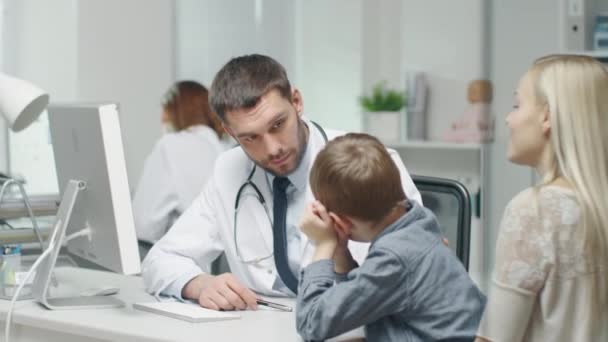 Au cabinet du docteur. Homme bien naturel Docteur parle et plaisante avec le petit garçon et sa mère . — Video