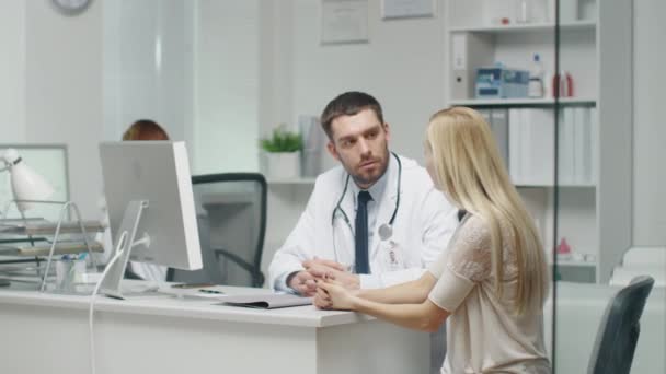 En la oficina del doctor, una paciente joven habla con su médico masculino . — Vídeos de Stock