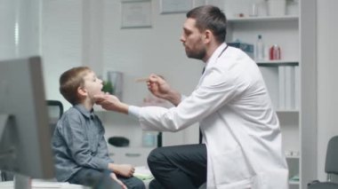 Erkek doktor kontrolleri genç çocuklar boğaz. Hemşire meşgul içinde belgili tanımlık geçmiş olduğunu.