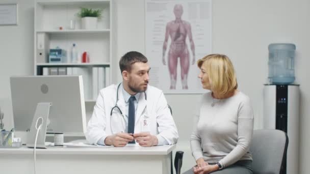 Médico Masculino Consulta Paciente Feminina Adulta. Eles falam e sorriem . — Vídeo de Stock