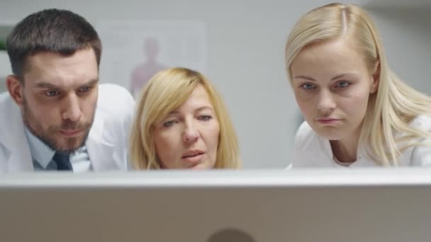 Gruppe von drei Medizinern, die Probleme am Desktop-Computer lösen. Sie gestikulieren und zeigen auf den Bildschirm. — Stockvideo