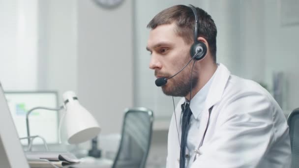 Male Doctor Consults Patients on the Internet. He Sits before His Personal Computer and Wears Microphone. — Stock Video