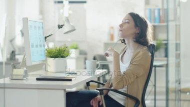 Yaratıcı kadın masaüstü bilgisayarını ofisinde oturan duruldu. Sorun çözme ve sandalyesinde girdap gibi düşünme.