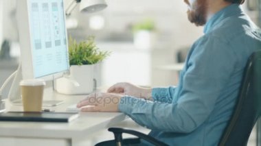 Yaratıcı ajansı ofisinde. Masaüstü bilgisayar kabilelerini gözlük erkekte sakallı. Kamera onun elinden yüzü ve bilgisayar ekranında bir Close-up taşır..