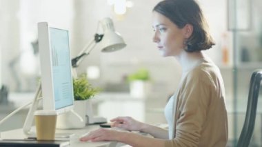 Genç güzel kadın masaüstü bilgisayar başında çalışıyor. Bir aydınlık ve Modern ofis masasında oturan.