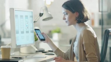Güzel Burnette onun Smartphone perde onun masaüstü bilgisayar ekranı ile karşılaştırır. Modern ve hafif ofiste her şey.