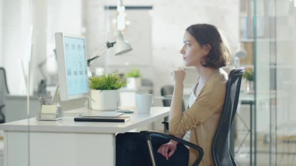 Kreativa korthåriga kvinnan arbetar vid sitt skrivbord eftertänksamt. Klunkar kaffe från en kopp och tänker på problemlösning. — Stockvideo