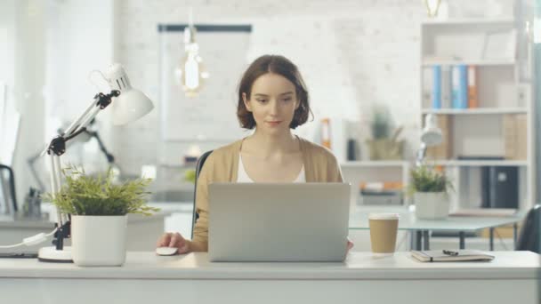 Portret Shot van een creatieve vrouw zit op haar bureau. Laptop gebruiken. Ze zit in een licht en Modern kantoor. — Stockvideo