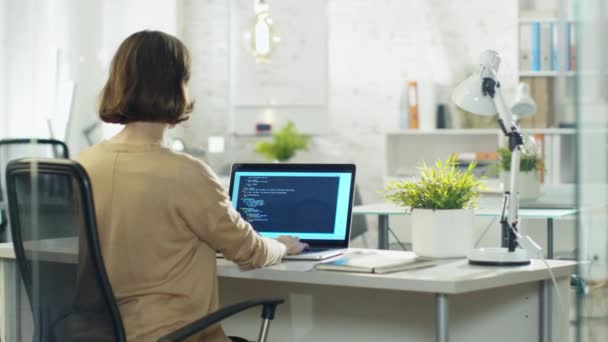 Молодая творческая женщина-разработчик пишет код на своем настольном компьютере. Она сидит в своем современном кабинете разработчика . — стоковое видео