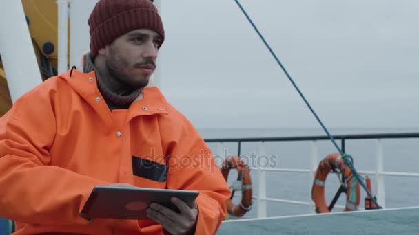 Випадковий одягнений рибалка використовуючи планшетний комп'ютер з навігаційними картами під час подорожі на кораблі . — стокове відео