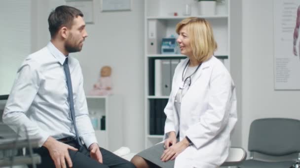 Half volwassen raadpleegt vrouwelijke arts jonge Man over zijn pijn in de onderrug. — Stockvideo