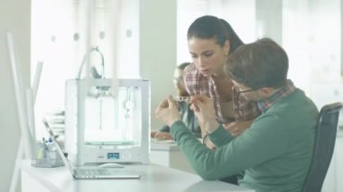 Mühendis 3d printerlere harcama maddeler kullanın ve basılı bileşen tartışmak. Arka plan iş arkadaşlarınızla işlerinde. Onların parlak Modern ofis konumudur.