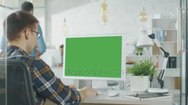 Yakın çekim yeşil ekran Pc ile onun masasında masada oturan bir adam. Arka plan bulanık ve parlak yaktı Office içinde insanlar aracılığıyla Office rutin nereye.