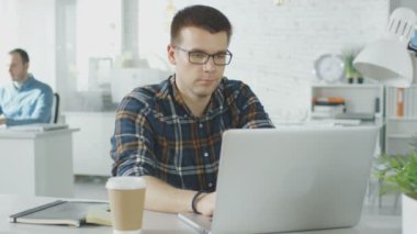 Yüzü açık onun Laptop çalışma onun yaratıcı Office masada oturan adam. Arka planda çalışan, onların masaüstü adam.