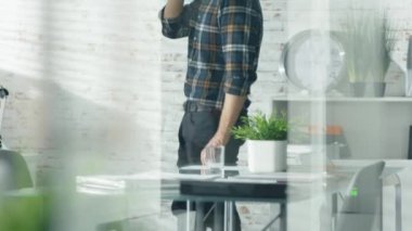 Yaratıcı bir camsı ofiste tembel tembel yürür ve bir akıllı telefon üzerinde görüşmeler dostum.