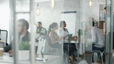 Meşgul bir yaratıcı büro içinde hafta içi. Çalışan insanlar çeşitli döküm. Ofis çalışanları kişisel bilgisayarları başında otur. Büyük masada oturumu planlama var.