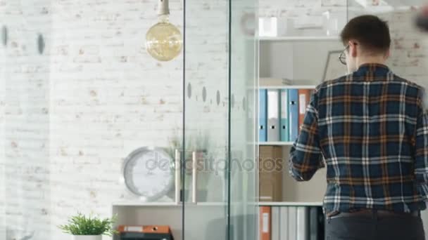 Man Enters Modern Office y saluda a su colega con un apretón de manos. Se sientan en la mesa y comienzan una reunión de negocios . — Vídeo de stock