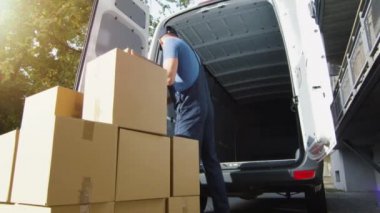 Teslimat adam yükler karton kutulara minibüsü. Ağır çekim.
