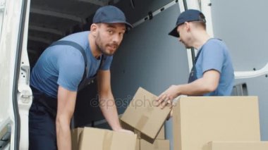 Ticari araç yükleme iki güçlü teslimat adam tam ağır çekimde karton kutu.