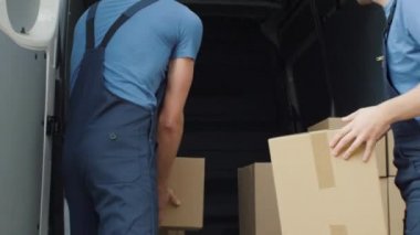 Ticari araç yükleme iki güçlü teslimat adam tam ağır çekimde karton kutu.