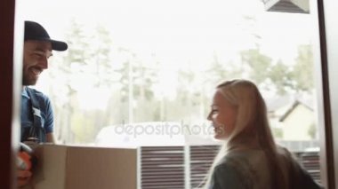 Güzel ev sahibi teslimatçı gülümseyen için kapıyı açar ve elektronik imza aygıtta imzalanmasından sonra parsel alır.