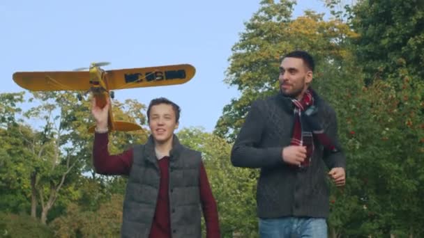 父と息子が公園中を実行するに向かってカメラの模型飛行機を起動します。スローモーション. — ストック動画