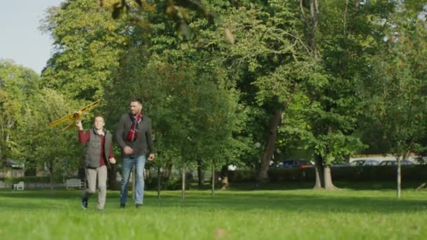 Vater und Sohn laufen mit Modellflugzeug im Park ein. — Stockvideo