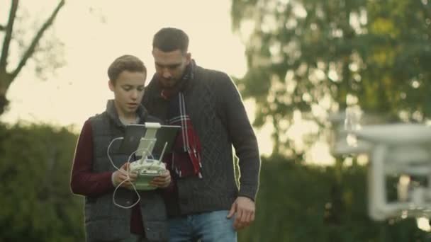 Son Controls Flying Drone mientras el padre mira. En el parque . — Vídeos de Stock