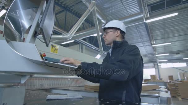 Ingenieur mit Hut richtet CNC-Maschine in der Fabrik ein — Stockvideo