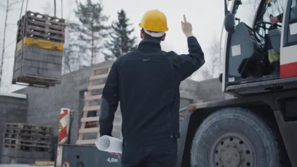 Byggande arbetare signaler till kranförare på byggarbetsplats — Stockvideo
