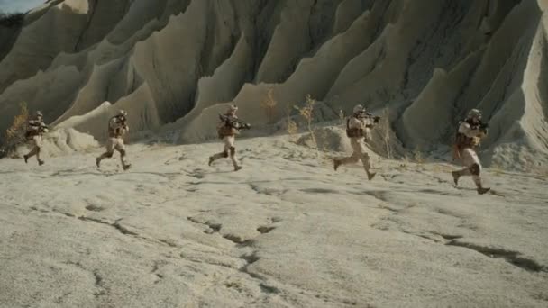 Отряд полностью экипированных и вооружённых солдат, бегущих в одном файле в пустыне. Шоу-движение . — стоковое видео