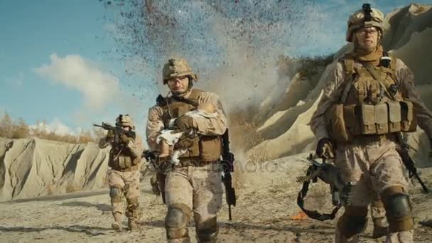 Soldados llevando un bebé mientras otros miembros del escuadrón los cubrían durante la batalla en el desierto. Moción lenta . — Vídeos de Stock