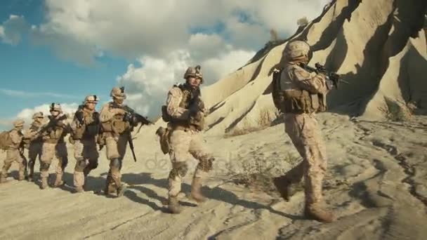 Esquadrão de soldados totalmente equipados e armados caminhando em um único arquivo no deserto . — Vídeo de Stock