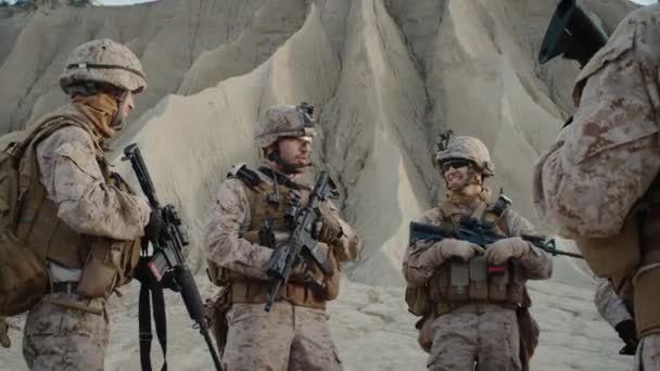 Skupina vojáků stojí v kruhu a poslouchá rozkazy od velitele během instruktáže před vojenskou operaci v poušti. — Stock video