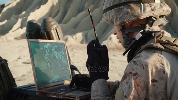 Soldado está usando computador portátil para rastrear o alvo e rádio para comunicação durante operação militar no deserto — Vídeo de Stock